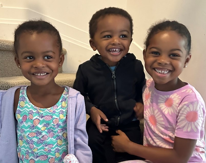 Three young children sitting on stairs, smiling